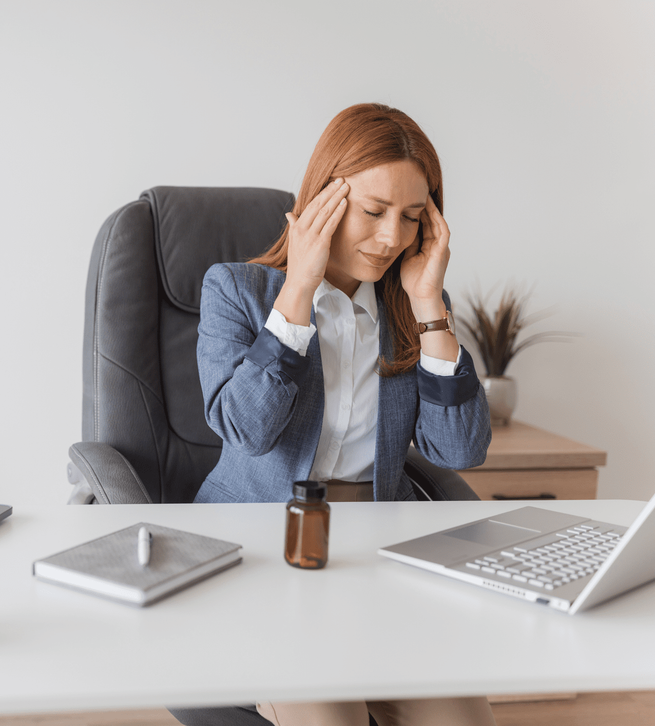 Woman experiencing stress or headache at her office desk.