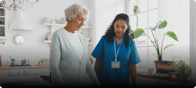 Elderly care worker assisting senior woman.