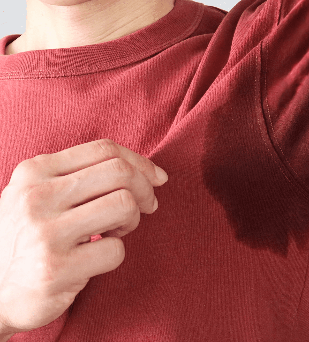 Person showing a sweat stain on red shirt under the arm.