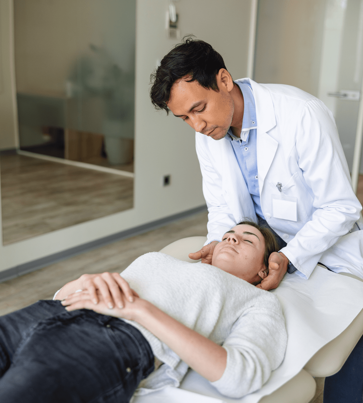 Doctor examining a patient's neck in a clinic.