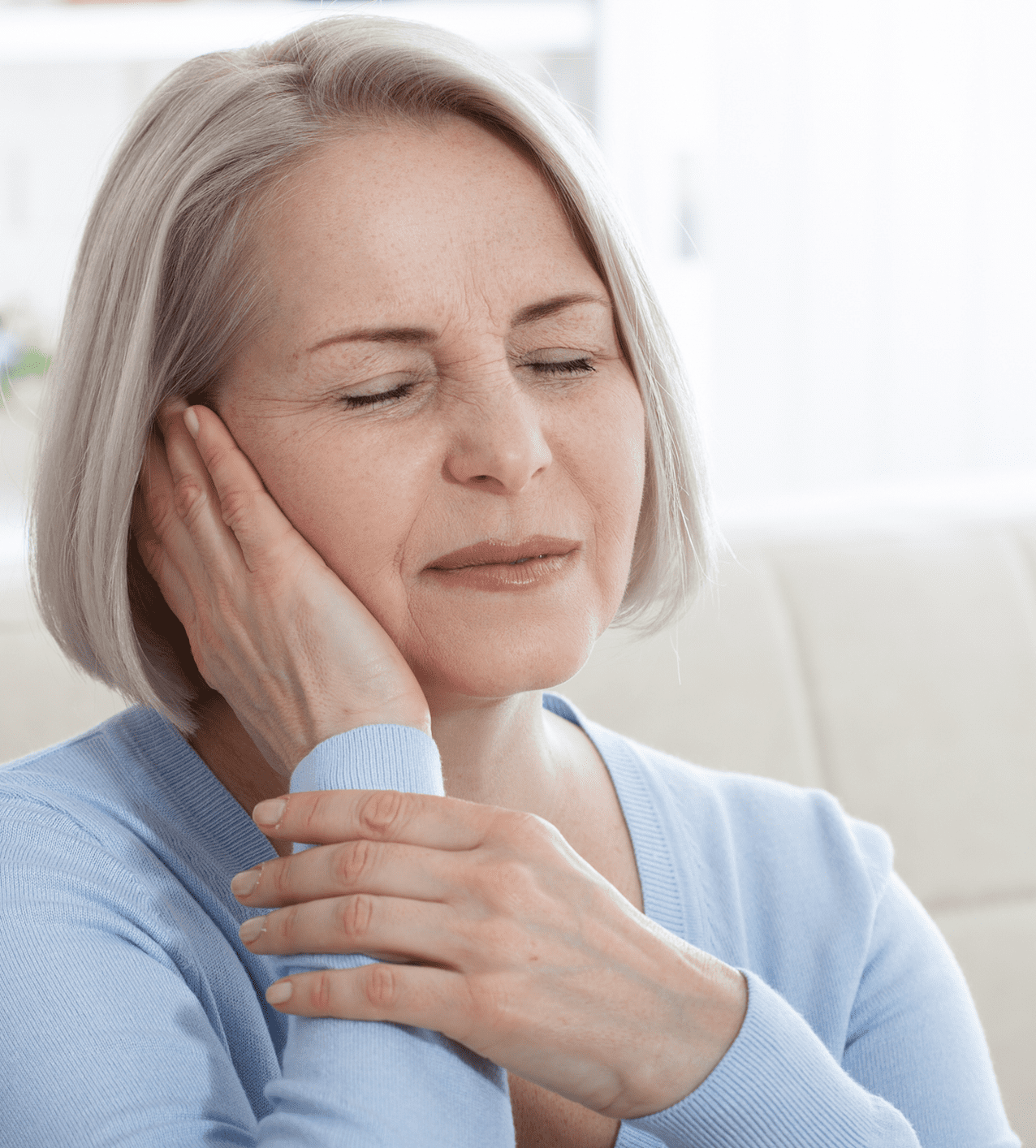 Woman experiencing ear pain while holding her wrist.