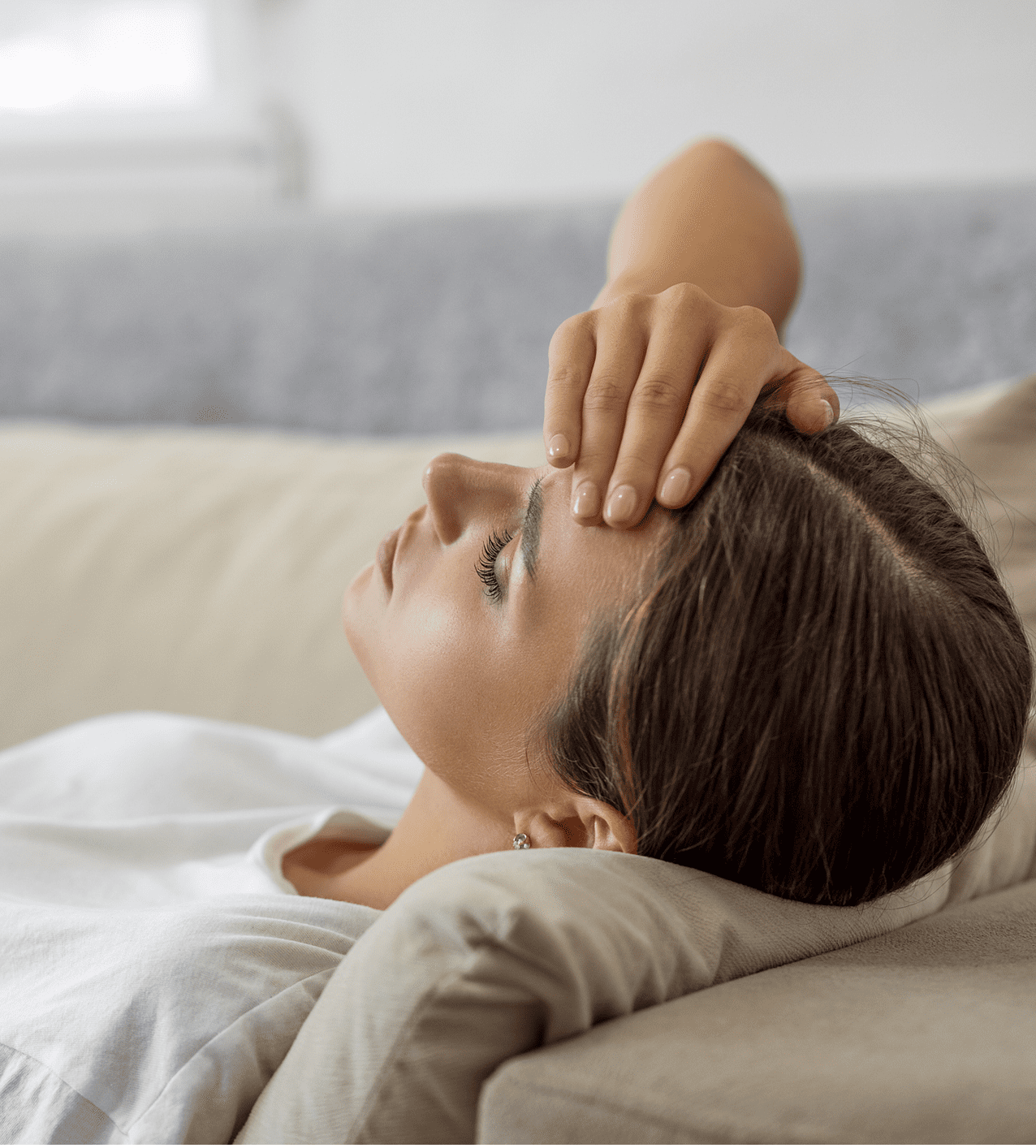 Woman lying down with eyes closed, resting her head on her hand.