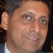 Close-up portrait of a smiling middle-aged man in formal attire.