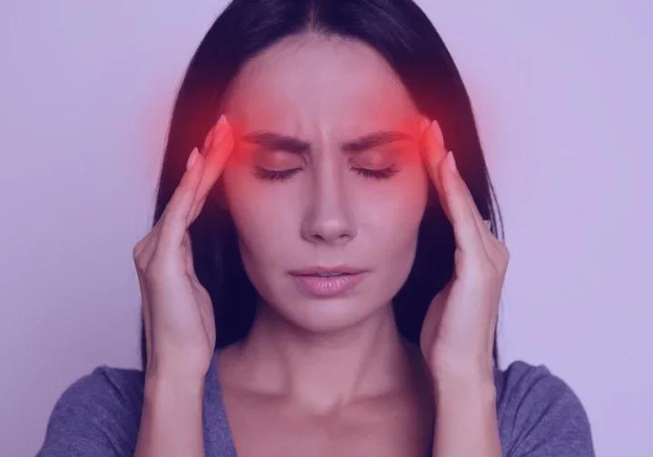 Woman with headache holding her temples.